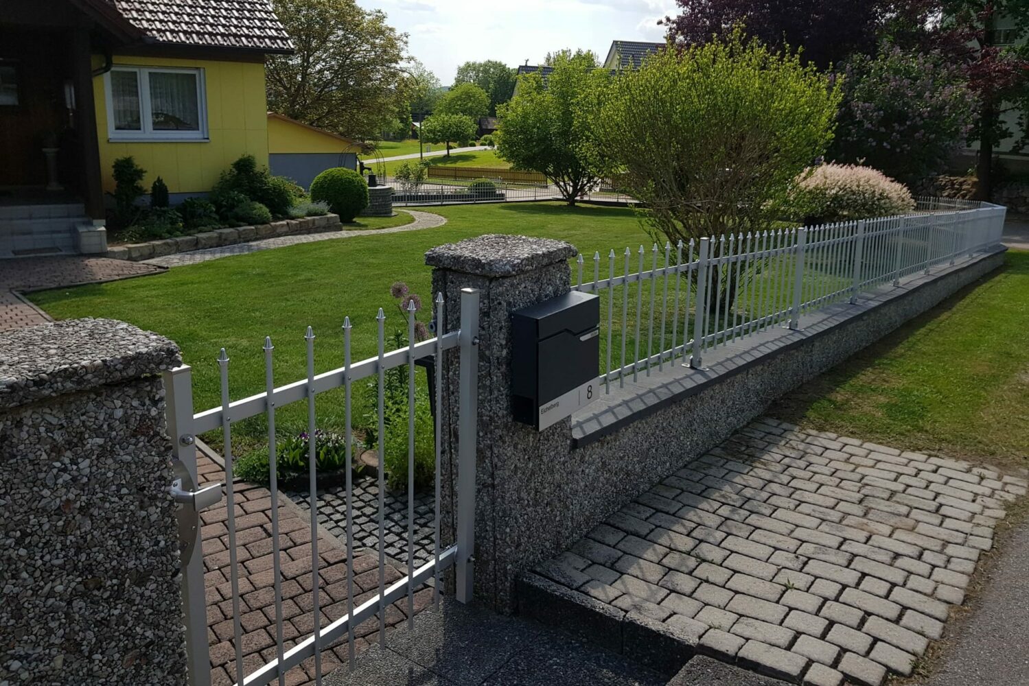 Aluzaun RIVA bei ansteigendem Gelände mit passgenauer Gartentür aus dem langlebigen Metall Aluminium